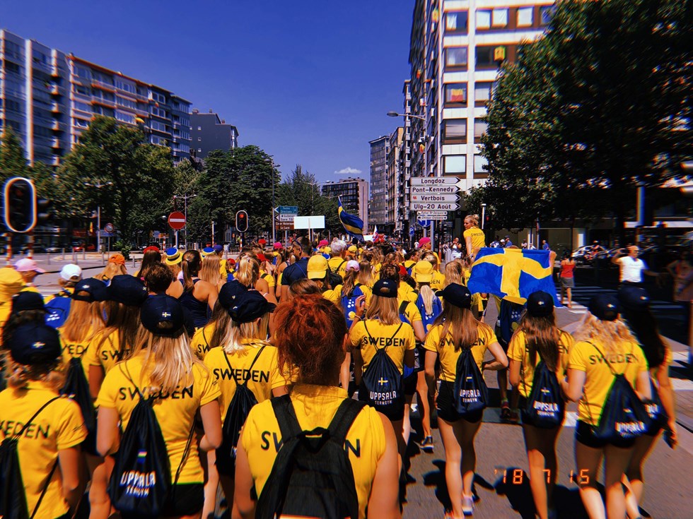 Personer går i parad med gula t-shirtar med texten Sweden på ryggen. 