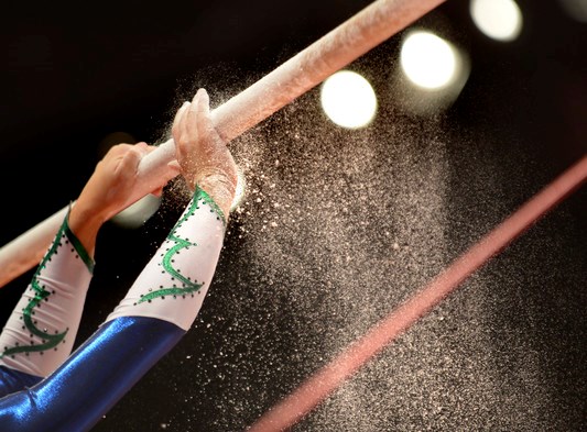 Kvinnlig artistisk gymnast kalkade händer på en barr. 