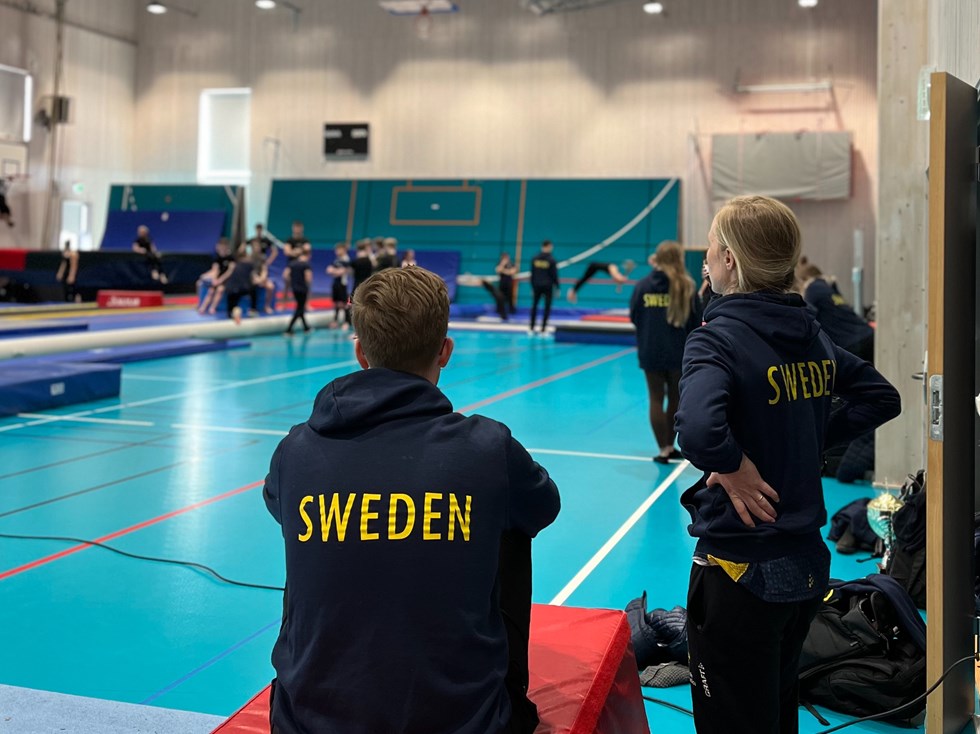 Personer i tröjor med Sweden på ryggen tränar i gymnastiksal