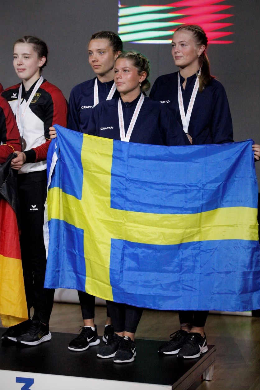 Svenskt lag på prispall håller i svenska flaggan